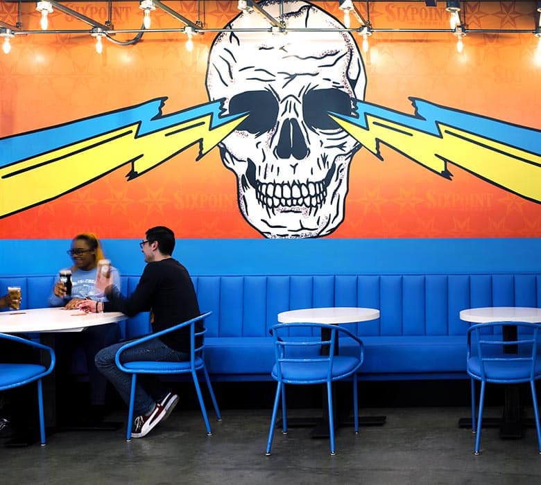 Sixpoint Brewery table seating and skull mural.